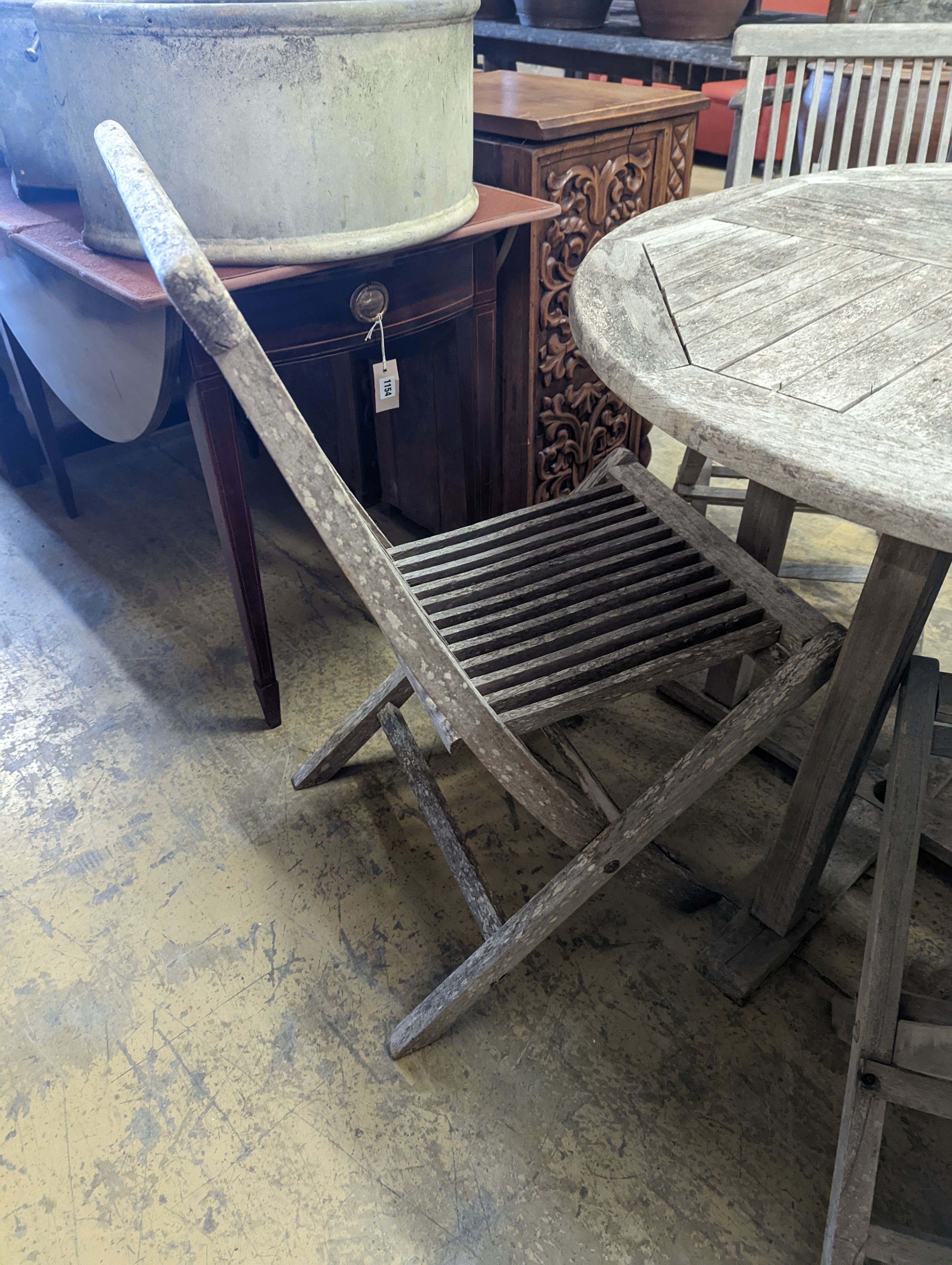 A circular weathered teak garden table, diameter 100cm, height 75cm together with four folding chairs